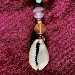 Puede incluir: Un accesorio para el cabello de color cobre con una parte superior en espiral, un dije de estrella, cuentas verdes y moradas y una concha de color crema. Diseñado para usar en el cabello.