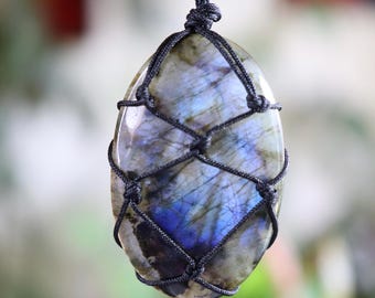 May include: A dark blue labradorite gemstone pendant wrapped in black cord. The stone has a unique iridescent sheen.