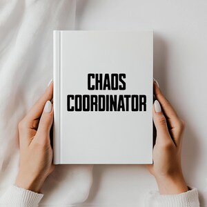 May include: A white notebook with the text "Chaos Coordinator" printed in black.