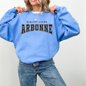 May include: A light blue sweatshirt with the text "Healthy Living Arbonne" in black.