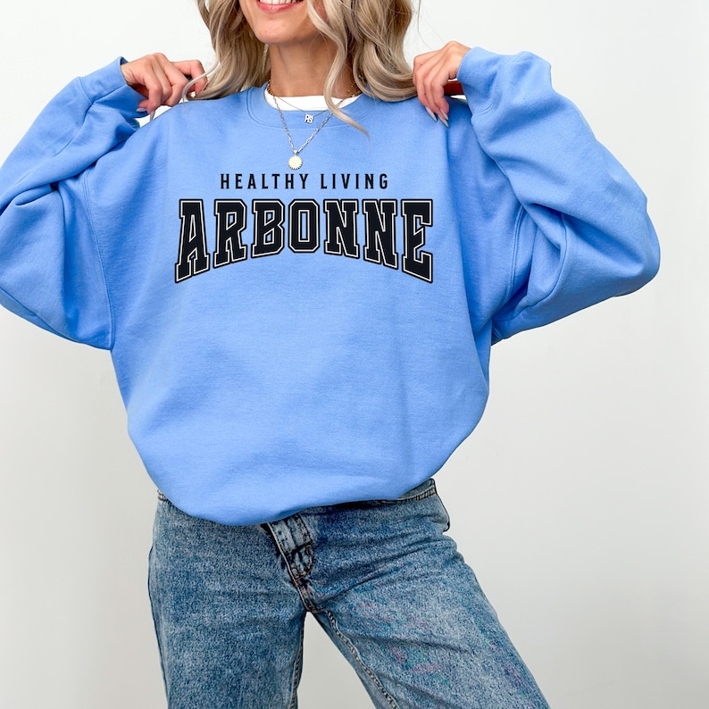 May include: A light blue sweatshirt with the text "Healthy Living Arbonne" in black.