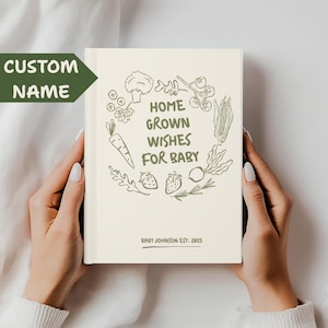 以下が含まれることがあります： 「HOME GROWN WISHES FOR BABY」の文字と、緑色の野菜や果物のイラストが描かれたクリーム色のジャーナル。ジャーナルには「BABY JOHNSON EST. 2025」の文字も含まれています。緑色の矢印型のラベルには「CUSTOM NAME」と書かれています。