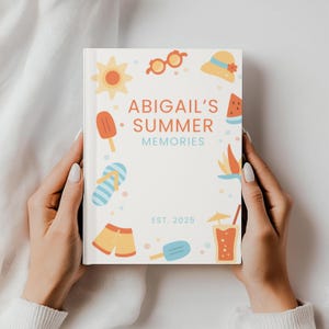 May include: A white journal titled "Abigail's Summer Memories" with colorful summer-themed illustrations. The cover features a sun, sunglasses, a hat, watermelon, a popsicle, flip-flops, shorts, and a drink. The journal is held by hands.