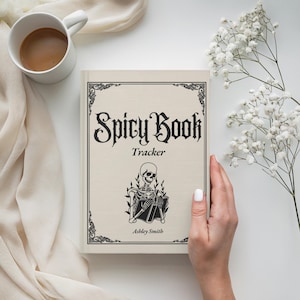May include: A beige book titled "Spicy Book Tracker" with a decorative border and a skeleton illustration. The book is held by a person's hand, and a cup of coffee and flowers are in the background.