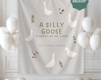 Op de afbeelding: Een lichtgrijze achtergrond met de tekst "A Silly Goose is Almost on the Loose" en ganzenillustraties. De achtergrond is 224x264 cm. Witte en beige ballonnen op de voorgrond, geschikt voor een babyshower.