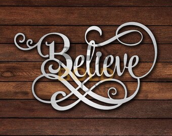 May include: A silver metal sign with the word "Believe" in a decorative script font. The sign is on a brown wooden background.