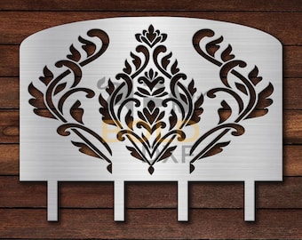 May include: A silver metal headboard with a decorative cutout design featuring a black floral pattern. The headboard has three metal posts at the bottom.