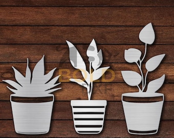 May include: Three metal plant silhouettes in pots against a wood grain background. The plants have different leaf shapes and pot designs, including a striped pot. The metal has a brushed finish.