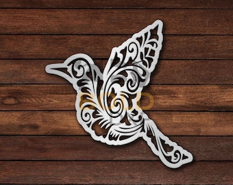 May include: A white metal cutout of a stylized bird with intricate floral designs. The bird is in flight with its wings spread wide.