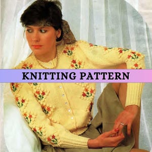 May include: A yellow knitted cardigan with a floral design. The cardigan has a button-up front and long sleeves. The model is wearing a skirt and has a headband on.