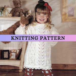 May include: A girl in a cream-coloured knitted dress featuring cable and lace patterns. The dress has a high neckline and long sleeves. The image displays the text "KNITTING PATTERN". She is holding a teddy bear.