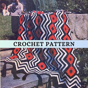 May include: A black, white, and red crochet blanket with a geometric pattern. The blanket has a fringe border and is folded on a set of stone steps.
