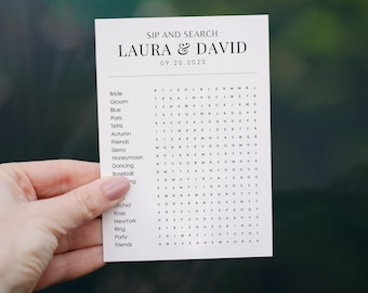 Op de afbeelding: Een witte kaart met een woordzoeker voor een bruiloft. De kaart heeft de titel "Sip and Search" en de namen "Laura & David" met de datum "09.20.2025". De woordzoeker bevat woorden zoals "Bride", "Groom", "Blue", "Paris", "Tetris", "Autumn", "Friends", "Sierra", "Honeymoon", "Dancing", "Baseball", "Orchid", "Rose", "New York", "Ring", "Party", en "Friends".