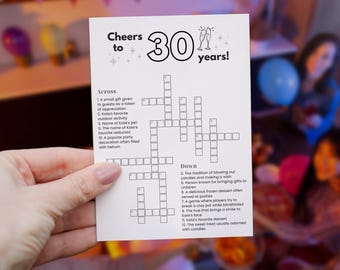 May include: A white card with a crossword puzzle for a 30th birthday celebration. The card reads "Cheers to 30 years!" with a crossword puzzle below. The puzzle includes clues like "Kate's favorite outdoor activity."