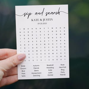 Peut inclure: Une carte blanche avec du texte noir qui dit "sip and search" avec les noms "Kate & Justin" et la date "09.20.2025". La carte contient un mot croisé avec les mots "bride", "groom", "blue", "paris", "tetris", "autumn", "friends", "sierra", "honeymoon", "dancing", "baseball", "wedding", "kate", "justin", "orchid", "rose", "New York", "ring", "party", et "friends".