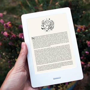 Puede incluir: Una lectora electrónica blanca que muestra una ilustración en blanco y negro de un sobre con una luna creciente y estrellas. El texto "Capítulo 2" es visible en el sobre. La lectora electrónica muestra texto sobre una historia ficticia.