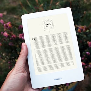 Puede incluir: Un lector electrónico blanco con un borde negro y una imagen en blanco y negro de un estallido de sol con el número 29 en el centro. El lector electrónico muestra una página de texto con una fuente negra.