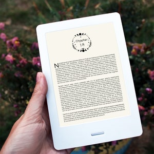 Puede incluir: Un lector electrónico blanco con una imagen en blanco y negro de un diseño de fases lunares y el texto "Capítulo 18". El lector electrónico está siendo sostenido en una mano.
