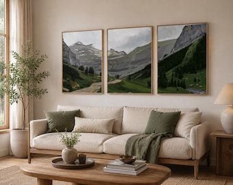May include: A triptych of framed wall art prints featuring a continuous mountain landscape painting with rocky peaks, green slopes, and a winding path. The artwork is displayed in three matching light wood frames hung side by side on a wall.