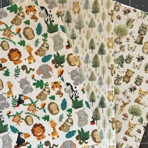 May include: Three sheets of fabric with different animal and nature patterns. The first sheet features a white background with a repeating pattern of jungle animals, including zebras, giraffes, elephants, and toucans. The second sheet features a white background with a repeating pattern of green trees. The third sheet features a white background with a repeating pattern of woodland animals, including owls, foxes, and raccoons.