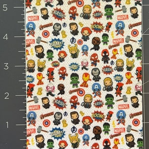 Op de afbeelding: Witte stof met een herhalend patroon van kleine cartoon Marvel-personages, waaronder Iron Man, Captain America, Thor, Hulk, Spider-Man en Deadpool. De stof bevat ook de woorden "Marvel", "Avengers", "Boom", "Crash" en "Bam!" in een comic-stijl lettertype.