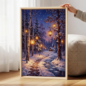 May include: A rectangular framed wall art print depicting a snowy winter forest scene at night. The image features a winding path, a small cabin, and glowing lanterns hanging from trees and lamp posts, casting warm light on the snow and stream.