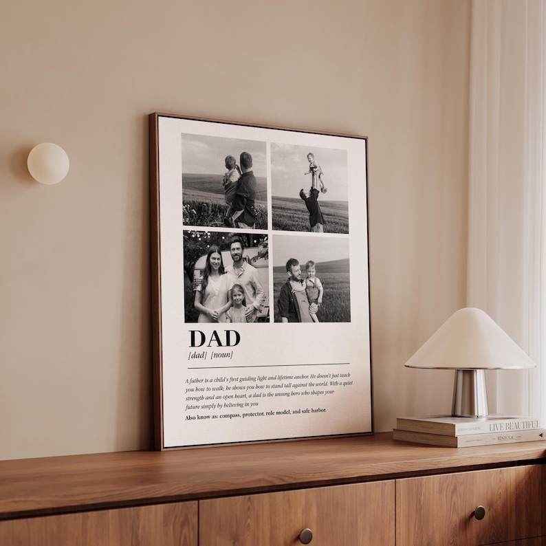 May include: A framed black and white print featuring four family photos and the word "DAD" in bold letters. Below the word is a definition of "dad". The print is displayed on a wooden cabinet.