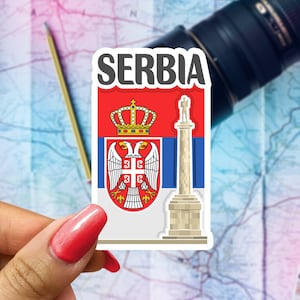 May include: A sticker featuring the coat of arms of Serbia. The sticker is white with a red, blue, and white flag in the background. The coat of arms features a double-headed eagle with a crown on top. The text "SERBIA" is printed in black at the top of the sticker.