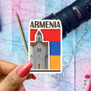 May include: A sticker with the word "ARMENIA" in white letters on a red background. The sticker features a gray church building with a red roof and a yellow and blue flag behind it.