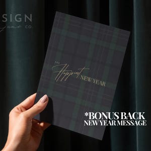 May include: A rectangular greeting card featuring a dark green and black plaid pattern. The text on the front reads "AND Happiest NEW YEAR" in a gold-colored script and serif font. The card includes a bonus back New Year message.