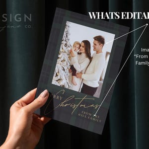 May include: A rectangular holiday card featuring a dark green plaid background with a central photograph of a family standing by a Christmas tree. The card includes the gold script text Merry Christmas and the printed text FROM THE HILL FAMILY.