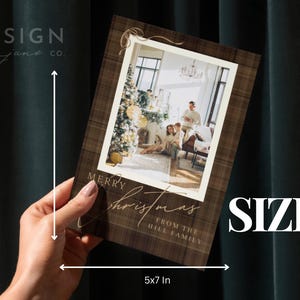 May include: A rectangular Christmas greeting card with a brown plaid border and a central photo of a family in a living room. The card features the text Merry Christmas from the Hill Family and includes a white measuring graphic indicating a 5x7 inch size.