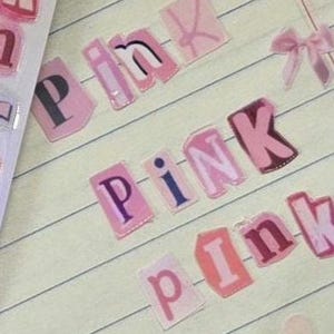 May include: Pink paper letters spelling out the word 'pink' on a lined notebook page. The letters are cut out and pasted on the page. There is a pink flower, a pink bow, and a pink heart sticker on the page.Magazine alphabet sticker Cutout letter scrapbook journal sticker cute sticker Trinket letter sticker fun alphabet sticker newspaper sticker funky letter sticker Junk Journal girlie Y2K retro sticker bullet