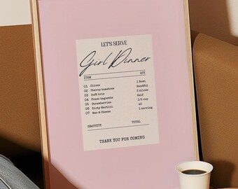 May include: A framed print with a pink background and a white receipt-style design that says "Let's Serve Girl Dinner". The print lists items like "olives", "cherry tomatoes", "soft brie", "fresh baguette", "extra virgin olive oil", "berry & cheese", and "meat & cheese".