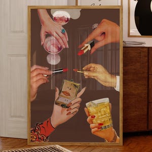 May include: A framed artwork featuring hands holding lipstick, a compact mirror, a cocktail, and a glass of wine. The hands are adorned with rings and red nail polish. The background is a solid brown color.