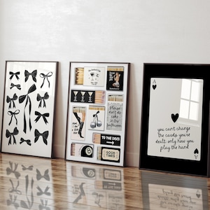 May include: Three framed prints with black frames. The left print features a white background with black bow designs. The center print features a collage of matchboxes with black and white designs. The right print features a black background with a white playing card, an ace of spades, and the text "you can't change the cards you're dealt: only how you play the hand".