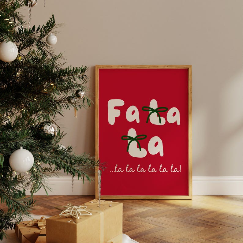 May include: A framed print with a red background and white text that says "Fa la la la la la!" with green bows on the letters.