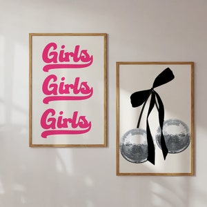 Może przedstawiać: Dwa oprawione wydruki, jeden z napisem "Girls" powt&oacute;rzonym trzy razy w r&oacute;żowym, ozdobnym pismem, a drugi z czarną kokardką i dwiema srebrnymi kulami pokrytymi brokatem.