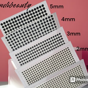 May include: Five sheets of black dot stickers in varying sizes from 1mm to 5mm. The stickers are arranged in rows on white rectangular sheets. The image has the text "mehndi beauty" in the upper left corner and the sizes are labeled on the right.