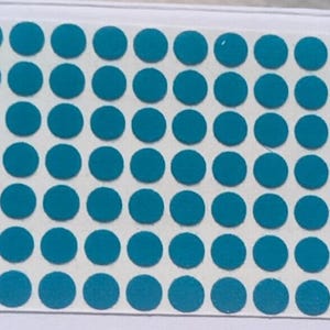 May include: A rectangular sheet of adhesive labels featuring a grid of numerous small, solid teal-colored circles. The circular stickers are arranged in uniform rows and columns on a white backing paper, providing a consistent and organized layout.