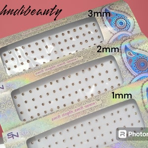May include: Three packages of self-adhesive rhinestones in gold, labeled with the text "हमारी संस्कृति, हमारी पहचान!" and "mehndibeauty". The packages are labeled with the sizes 1mm, 2mm, and 3mm.