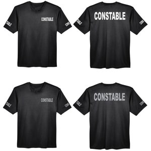 May include: Two black t-shirts with the word "CONSTABLE" printed in white on the front and back. The word "TABLE" is printed on the left sleeve and "CONS" is printed on the right sleeve.