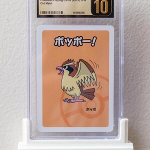 Puede incluir: Una carta Pok&eacute;mon Pidgey calificada del set japon&eacute;s Old Maid de 2019, encerrada en un soporte protector transparente. La tarjeta presenta una ilustraci&oacute;n de dibujos animados de una criatura parecida a un p&aacute;jaro. El soporte est&aacute; calificado como Pristine 10 por CGC.