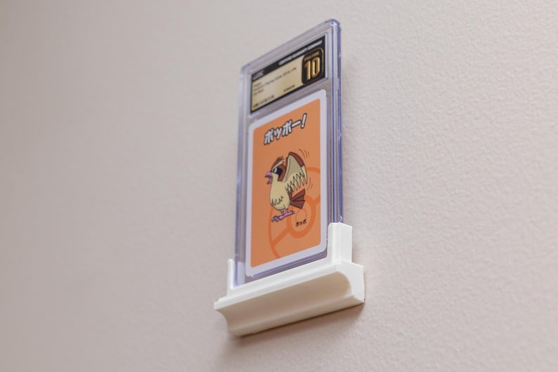 Puede incluir: Una tarjeta coleccionable calificada en una funda de pl&aacute;stico transparente, montada en un expositor de pared blanco. La tarjeta presenta una ilustraci&oacute;n de p&aacute;jaro de dibujos animados y texto japon&eacute;s. La funda est&aacute; calificada con un 10.