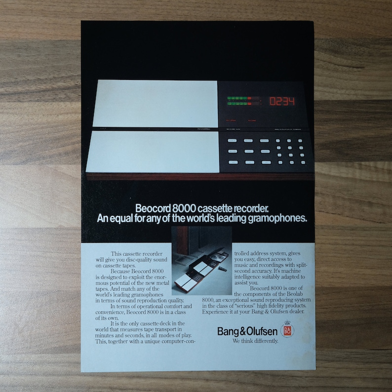 May include: A black and white advertisement for the Beocord 8000 cassette recorder from Bang & Olufsen. The ad features a close-up of the recorder with a digital display showing "0234". The text reads "Beocord 8000 cassette recorder. An equal for any of the world's leading gramophones."