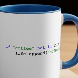 May include: White coffee mug with a blue rim and handle. The mug has a code snippet printed on it that reads: "if "coffee" not in life: life.append("coffee")"