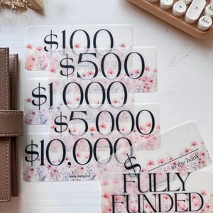 May include: Five transparent cards with a floral design and the text "$100", "$500", "$1,000", "$5,000", and "$10,000". A sixth transparent card with a floral design and the text "FULLY FUNDED in the bank".