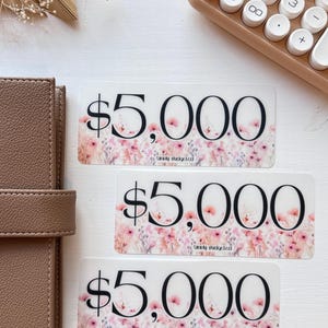 May include: Three transparent stickers with a floral design and the text "$5,000" and "Simply Budgeted".