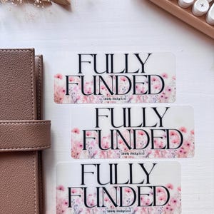 May include: Three white stickers with pink floral designs and the text "FULLY FUNDED" in black. The text "Simply Budgeted" is also included on each sticker.