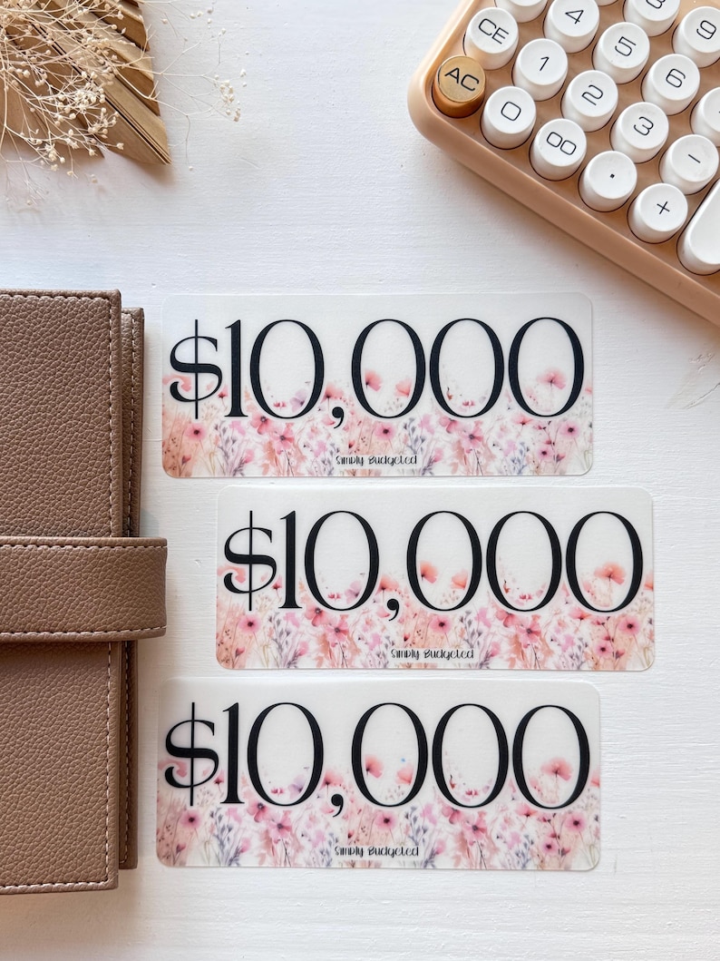 May include: Three transparent stickers with a floral design and the text "$10,000" and "Simply Budgeted" printed on them.